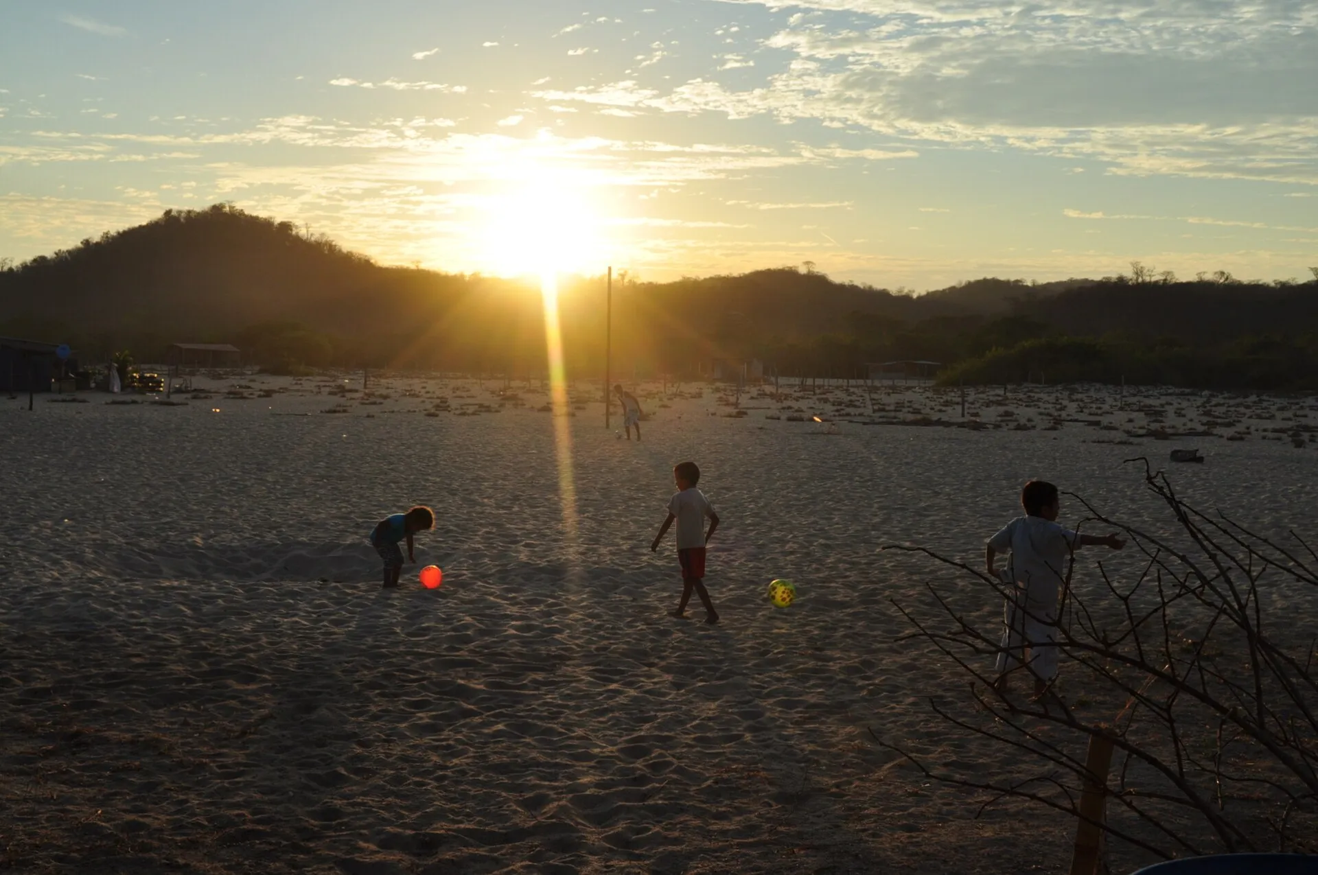 Niñas y niños juegan con una pelota en una playa de Oaxaca al atardecer
