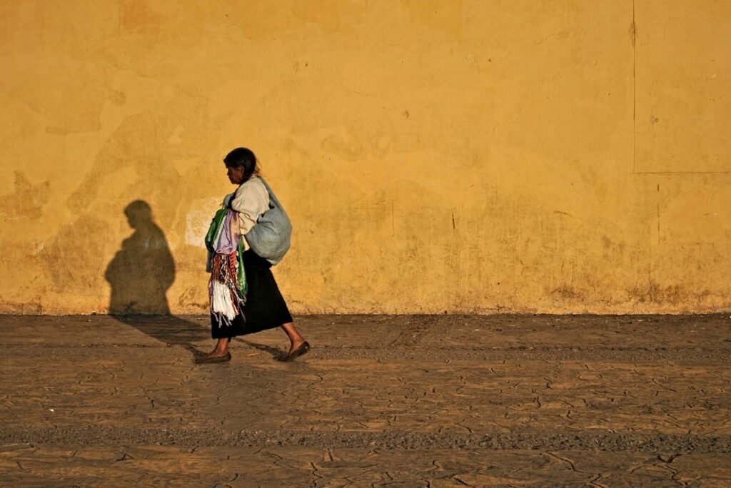 Mujer con falda tradicional camina frente a un muro amarillo en San Cristóbal de las Casas, Chiapas
